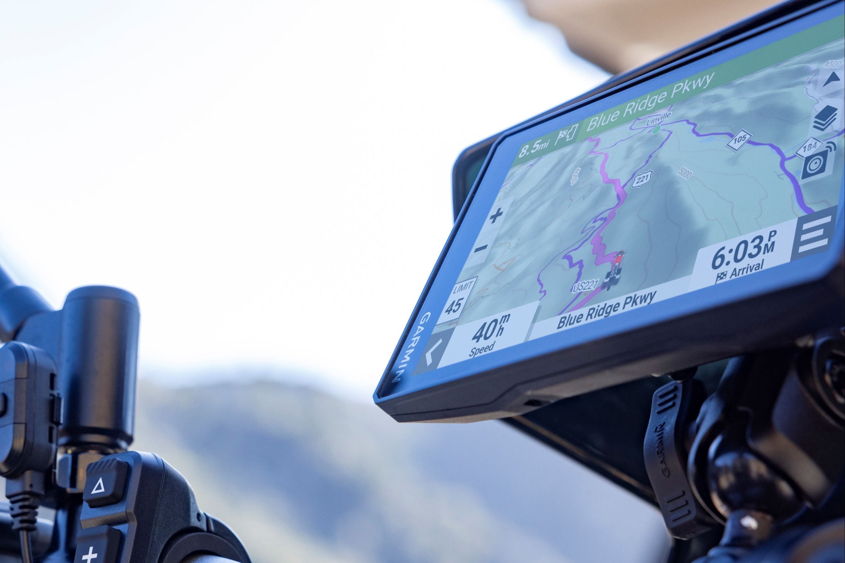 Motorcycle handlebar with GPS device and rearview mirror against a blurred background