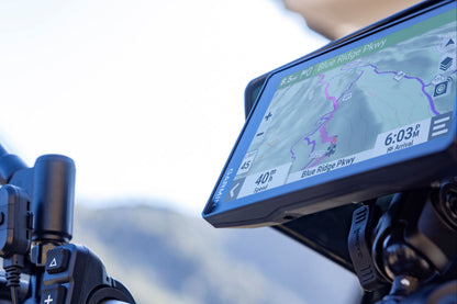 Motorcycle handlebar with GPS device and rearview mirror against a blurred background
